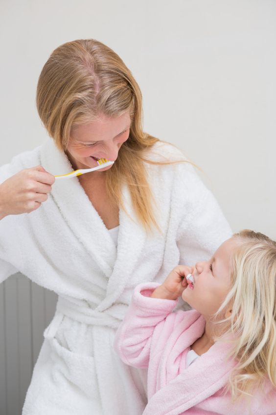 Mother and daughter brushing their teeth